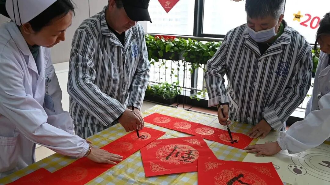 今年春节，刘在德（左二）用恢复的右手写毛笔字。通讯员赵炯 摄
